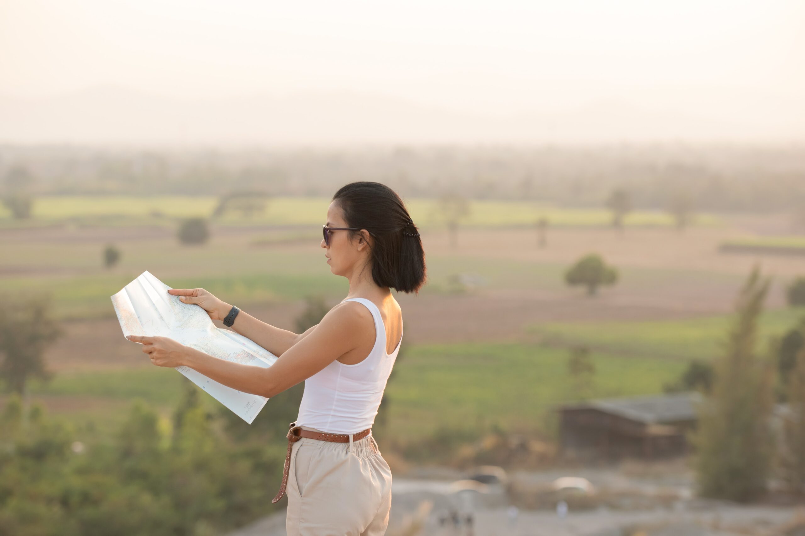 Female traveler holding a map and surveying open land, symbolizing exploration of land for sale in Cyprus.