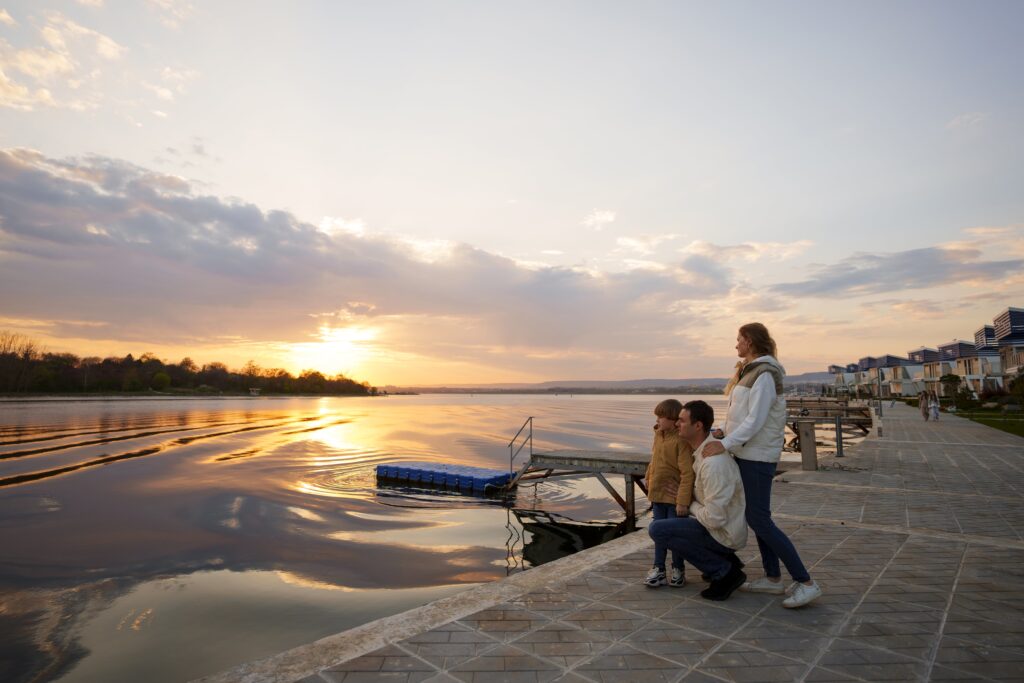 Family enjoying sunset by the waterfront near modern homes in Cyprus, symbolizing a serene lifestyle and real estate opportunities