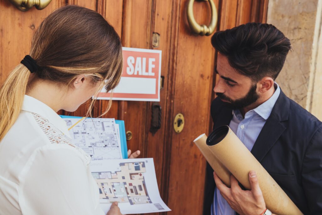Real estate agents reviewing floor plans in front of a property for sale in Larnaca, Cyprus.