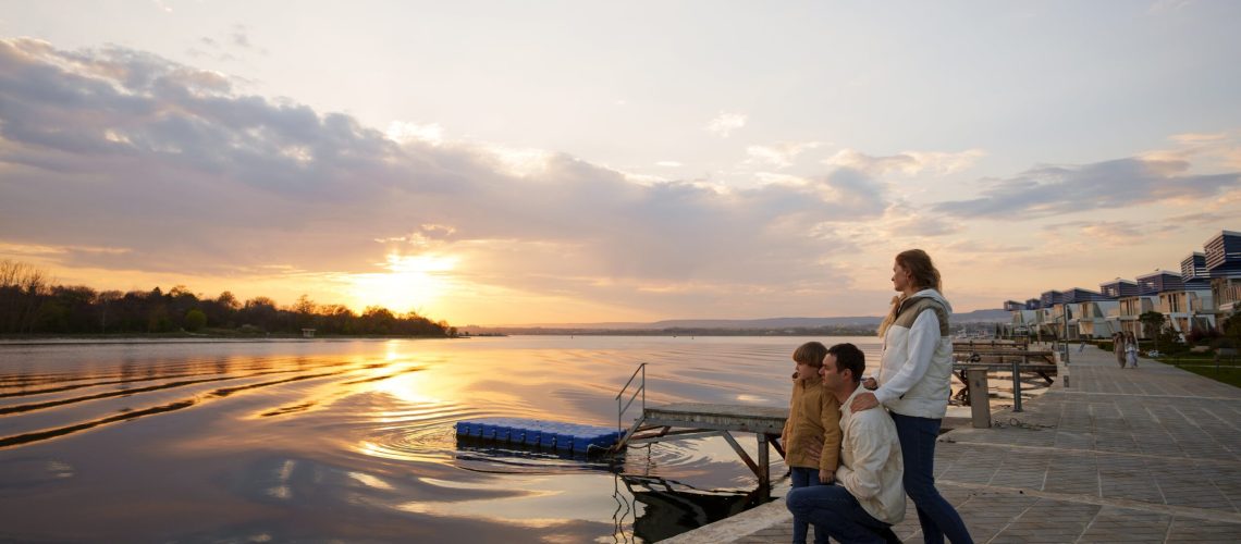 Family enjoying sunset by the waterfront near modern homes in Cyprus, symbolizing a serene lifestyle and real estate opportunities